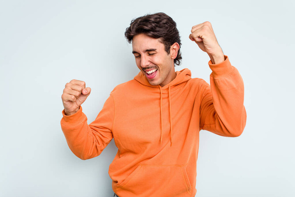 Young hispanic man isolated on blue background dancing and having fun. - Photo, Image
