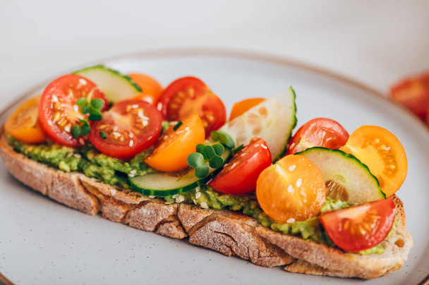 Tasty open sandwich from toasted sourdough bread with mashed avocado and fresh tomatoes - Photo, image
