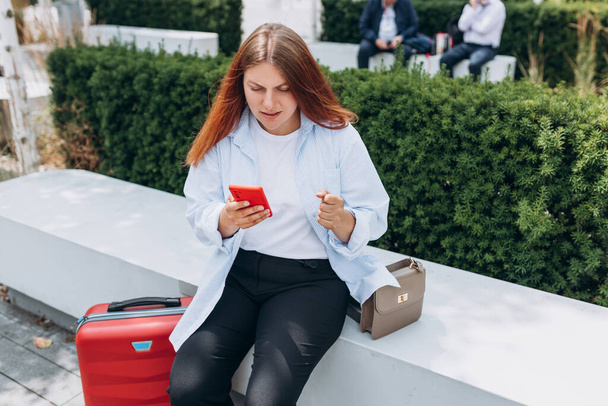 Rozrušená mladá žena, která používá chytrý telefon a čte špatné zprávy, smutná zamyšlená dívka sedící na schodech na městské ulici. Negativní emoce - Fotografie, Obrázek