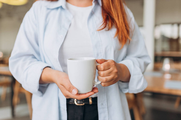 Detailní záběr ženských rukou s džbánem nápoje. Krásná dívka drží šálek čaje nebo kávy. Prázdná šablona pro propagační textovou zprávu nebo propagační obsah - Fotografie, Obrázek