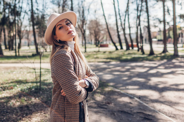 Stylish young woman wears hat and blazer walking in fall park. Autumn female clothes and accessories. Fashionable look. Space - Foto, Bild