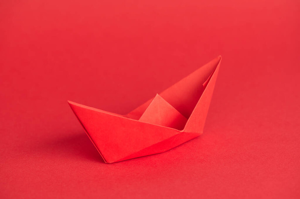 barco de papel rojo solo sobre fondo rojo con espacio de copia - Foto, imagen