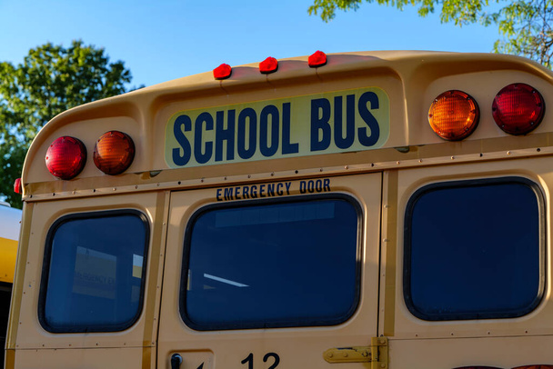 Na szczycie żółtego autobusu szkolnego ze światłami i tekstem. Zbliżenie do błękitnego nieba jesienią. Wracając do koncepcji szkoły. Odbiór. Wysokiej jakości zdjęcie - Zdjęcie, obraz