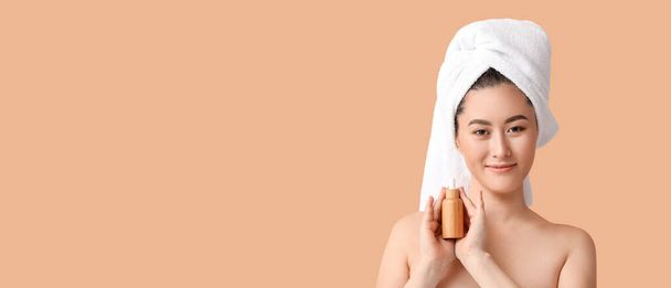 Joven mujer asiática sosteniendo botella de suero cosmético sobre fondo beige con espacio para el texto - Foto, Imagen