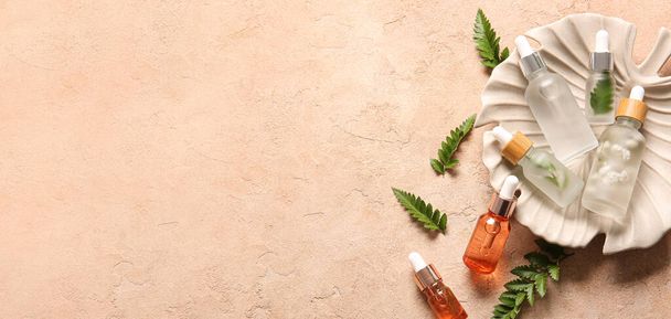 Bottles of cosmetic serum and fern leaves on beige background with space for text - Photo, image