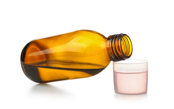 Бутылка сиропа от кашля и чашка на белом фоне - Фото, изображение