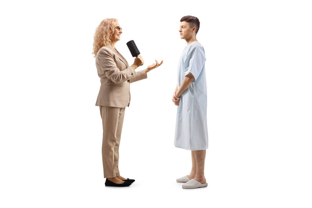 Female reporter interviewing a young male hospitalized patient isolated on white background - Foto, immagini