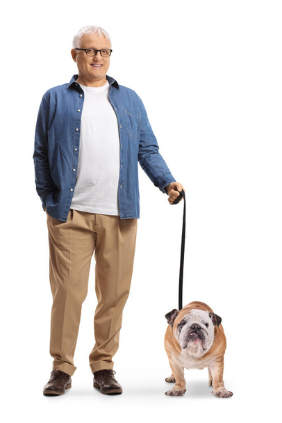 Full length portrait of a smiling mature man with a bulldog on a lead isolated on white background - Foto, imagen