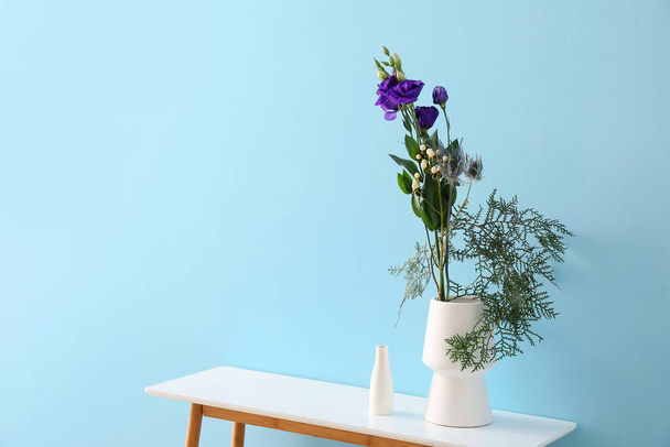 Wazony z pięknym ikebana na stole w pobliżu niebieskiej ściany - Zdjęcie, obraz