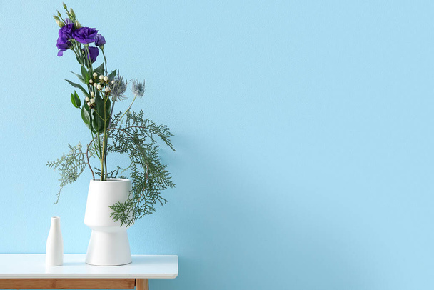 Vases with beautiful ikebana on table near blue wall - Foto, Imagem