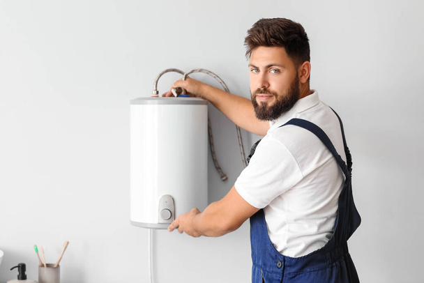 Male plumber installing boiler in bathroom - Foto, immagini