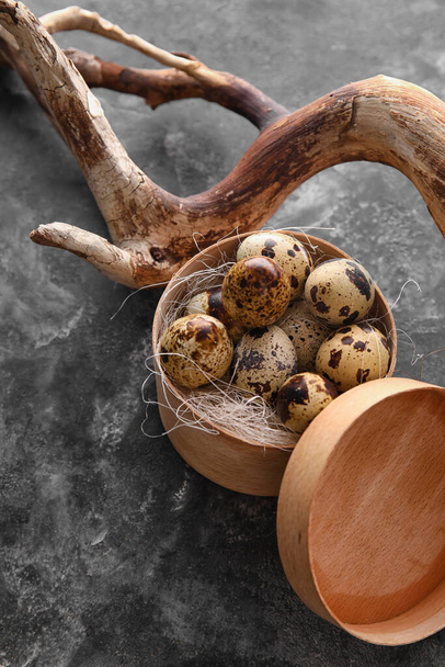 Ξύλινο κουτί με αυγά ορτυκιού και κλαδί δέντρου σε φόντο grunge, closeup - Φωτογραφία, εικόνα