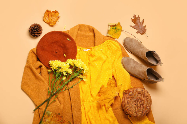 Stilvolle Frauenkleidung, Blumenstrauß und Herbstblätter auf beigem Hintergrund - Foto, Bild