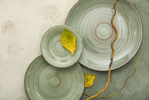 Beautiful plates with autumn leaves and tree branches on grunge background - Fotografie, Obrázek