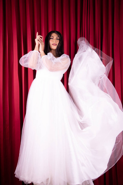 Asian woman posing in a white wedding dress and had black hair inside the red curtain room - Zdjęcie, obraz