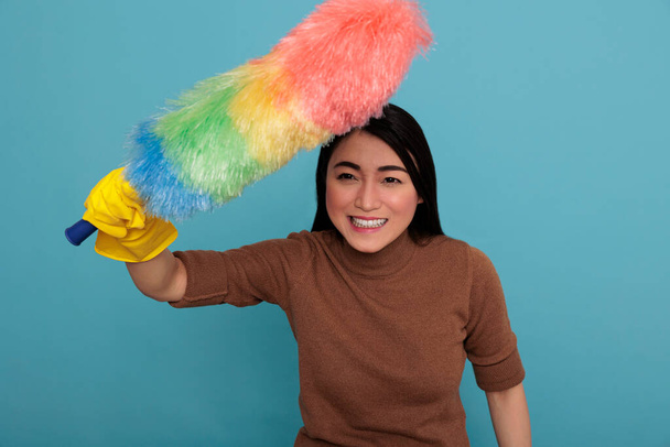 Souriant heureux et riant jeune femme de ménage asiatique au travail gant jaune tenant brosse à poussière colorée, Nettoyage concept maison, Se sentir heureux et positif des corvées, - Photo, image