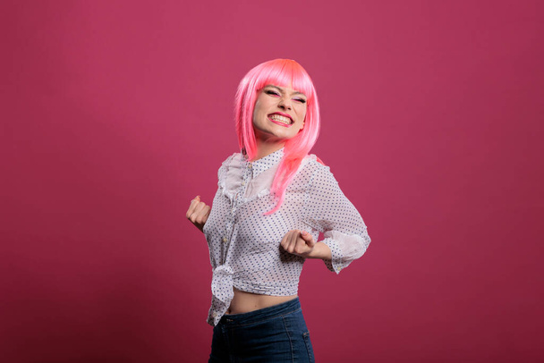 Joyful confident woman celebrating big win and success, posing in front of camera over pink background. Feeling happy and excited about achievement and wonderful triumph, winner style. - Foto, imagen