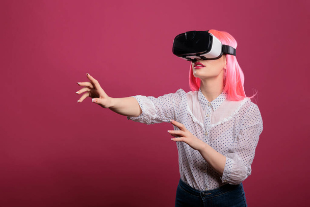 Modelo de belleza con gafas de realidad virtual con visión 3D, simulación visual interactiva en gafas vr. Experiencia futurista electrónica con innovación tecnológica aumentada sobre fondo rosa. - Foto, Imagen