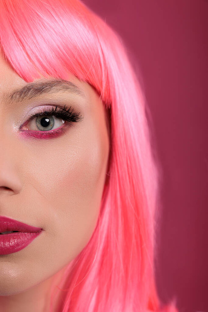 Portret modelki urody przedstawiający połowę twarzy przed kamerą w studiu, o różowych włosach i kosmetykach do makijażu. Stylowe słodkie kobieta uczucie zmysłowe i beztroskie, zabawy na tle. Zamknij się.. - Zdjęcie, obraz