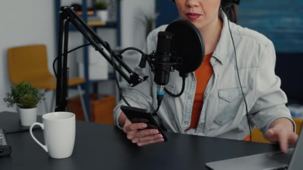 Famous online live radio talk show using smartphone to answer audience messages. Popular social media influencer talking with public on live chat on mobile cell phone. Studio shoot - Video, Çekim