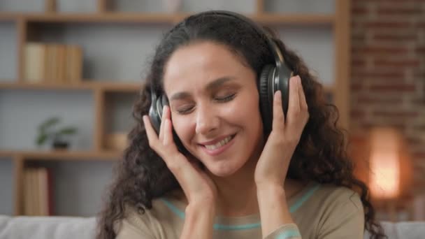 Portrait à la maison heureux calme inspiré hispanique latino caucasien 30s femme avec son de haute qualité audio enjoint dans les écouteurs modernes relaxant avec les yeux fermés écouter de la musique mélodie danse avec les mains - Séquence, vidéo