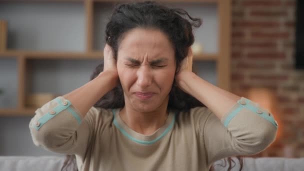 Portret Spaanstalige blanke vrouw geïrriteerd radeloos meisje zit thuis dekt oren met handen negeert weigert te luisteren horen beschermt tegen lawaai schreeuwen luide geluiden houdt hoofd lijdt hoofdpijn - Video