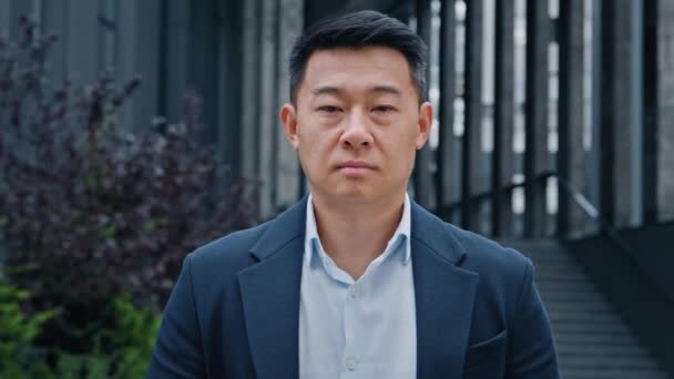 Front view close up portrait Asian Korean Chinese Japanese adult 40s middle-aged serious calm confident smart man businessman leader boss manager worker entrepreneur investor employer posing in city - Footage, Video