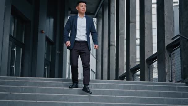 Stílusos öltönyös befektető középkorú ázsiai férfi üzletember főnök vezető munkás sétál le lépcsőn lépcső jön ki elhagyva iroda város cég épület rohanó találkozó szabadban - Felvétel, videó