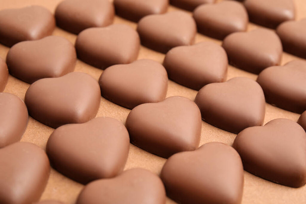 Tasty heart shaped chocolate candies on brown background, closeup. Valentine's day celebration - Foto, Imagen