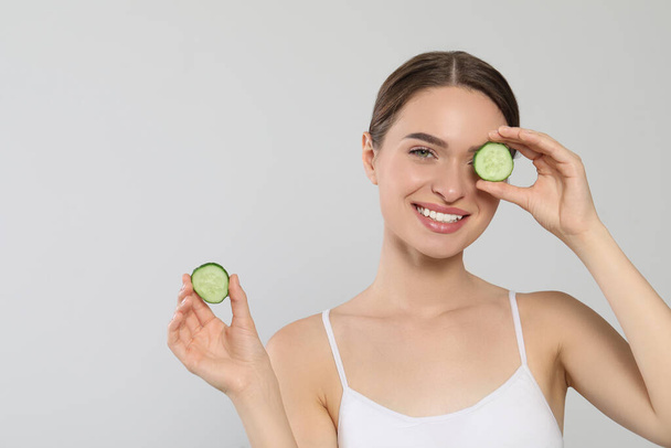 Young woman with cucumber slices on white background, space for text. Eye skin care - Fotó, kép