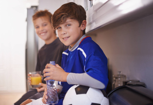 Chłopcy będą chłopcami. dwóch młodych chłopców pijących zimne drinki po treningu piłki nożnej - Zdjęcie, obraz