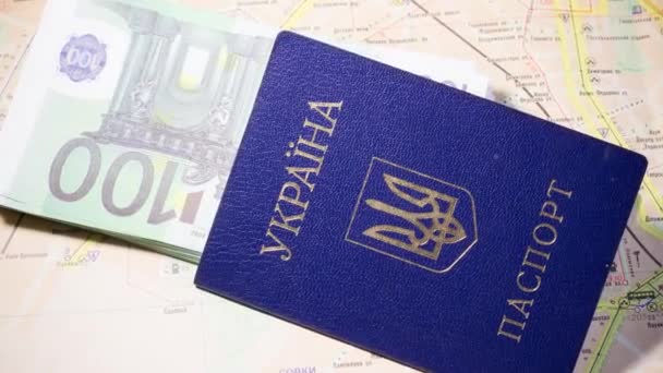 Український паспорт з банкнотами лежить на карті. Знищення біженців через війну в Україні - Кадри, відео