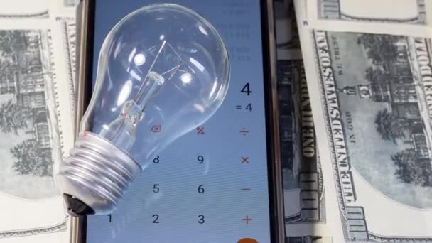 Auf einem Taschenrechner und Geldscheinen lag eine Glühbirne. Stromsparen in der Ukraine wegen des Krieges - Filmmaterial, Video