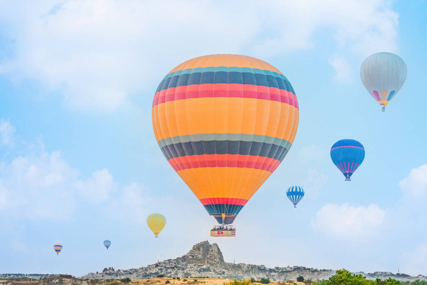 panoramic landscape scenery of hot air balloons flying over Goreme town in Cappadocia region Turkey with blue sky background - Foto, Imagen