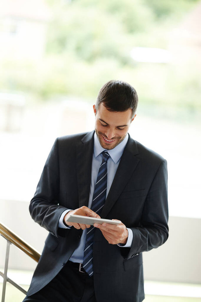 I cant believe how simple this is. A handsome young businessman using a digital tablet while standing indoors - Foto, imagen