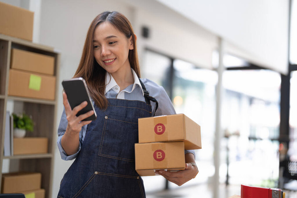 kisvállalkozás tulajdonos gazdaság telefon és kiskereskedelmi csomag csomag dobozok ellenőrzése kereskedelmi szállítási megrendelés okostelefon segítségével mobil app technológia - Fotó, kép