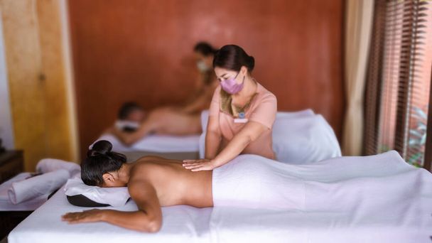 Couple men and women getting a Thai massage. European men and Thai women getting a massage in a luxury hotel in Thailand - Photo, Image