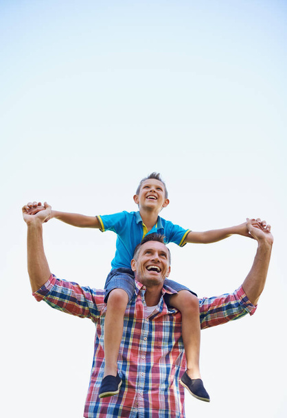 A dad is a sons first hero. A low angle shot of a happy father carrying his young son on his shoulders - Foto, immagini
