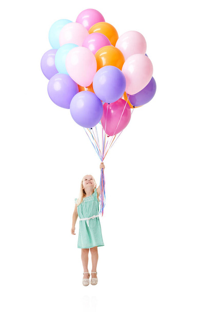 Fliege mich zum Mond. Studioaufnahme eines süßen kleinen Mädchens, das vor weißem Hintergrund ein Bündel Luftballons in der Luft hält - Foto, Bild