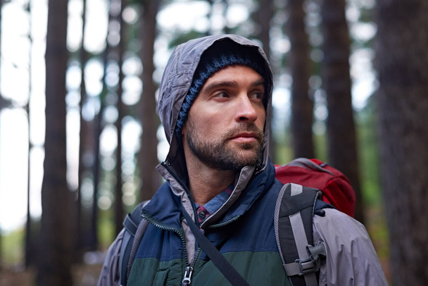 Der Mensch auf Mission. Porträt eines jungen Mannes mit Rucksack beim Wandern im Wald - Foto, Bild