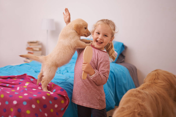Bak anne, üzerime atladı. Küçük bir kızın yatak odasında köpek yavrusuyla oynarken çekilmiş bir fotoğrafı. - Fotoğraf, Görsel