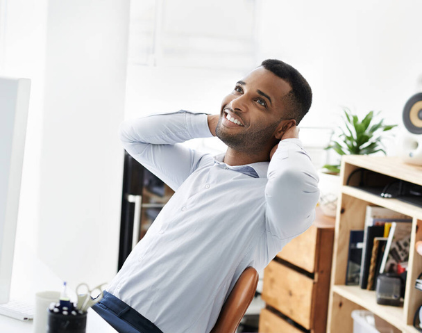 Work is a dream. A handsome young african american businessman sitting at his desk and relaxing - Photo, Image