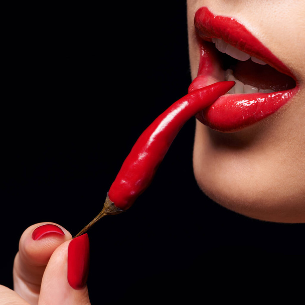 Diğer yasak meyve. Ağzına kırmızı biber tutan bir kadının yakın çekimi. - Fotoğraf, Görsel