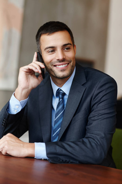 Chatting to a fellow coworker. A handsome young businessman taking a call on his mobile - Foto, Imagem
