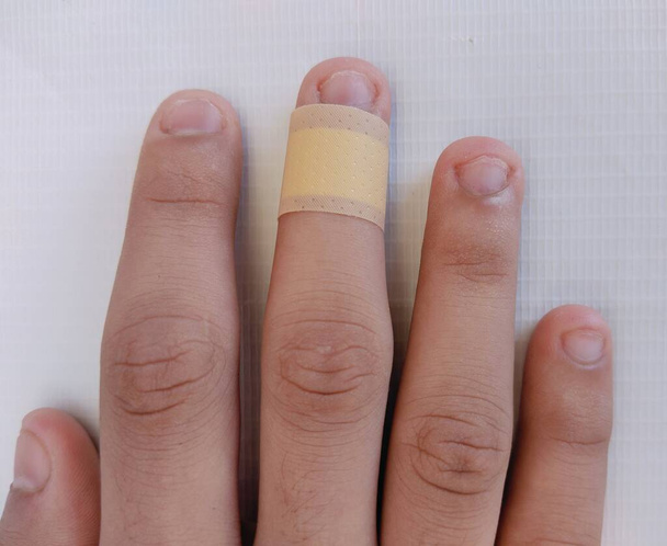Venda de banda adhesiva en el dedo herido corte humano pegando yeso en la cinta de primeros auxilios médica de corte menor en los dedos heridos de cerca ver imagen foto  - Foto, imagen