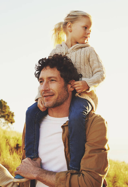 Quiero mostrarle el mundo. un padre cargando a su pequeña niña sobre sus hombros mientras camina al aire libre - Foto, imagen