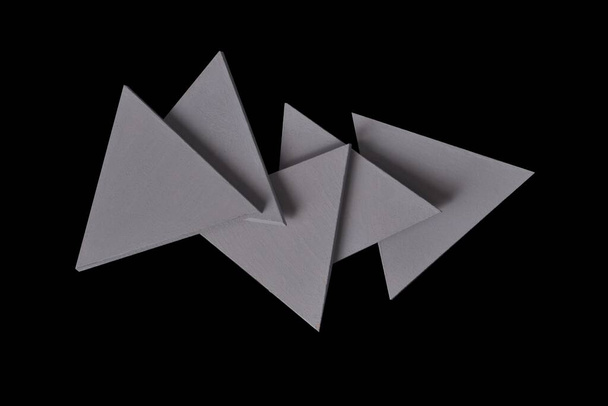 abstract shaped grey triangles solid pieces on black background. - Photo, Image