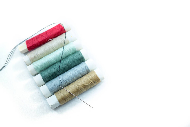 白い背景に隔離された様々な色や縫製針の縫製糸の行. - 写真・画像