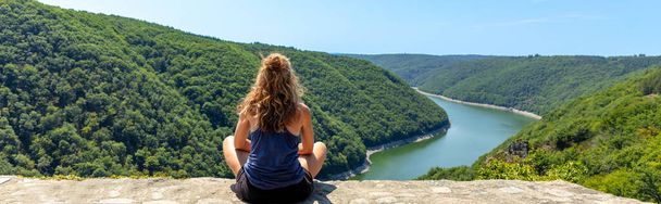 Rear view of woman sitting and looking at river dordogne and mountain - 写真・画像