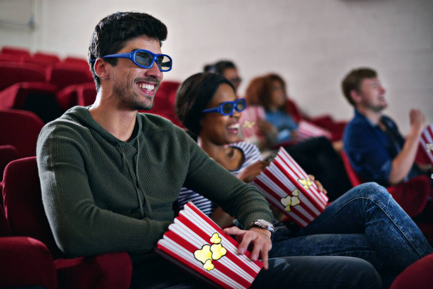 Finest quality entertainment. a man smiling while watching a 3D movie at the cinema - Foto, imagen